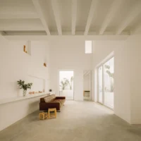 Tall white living space with a small high window, a leather sofa and a glass door to a patio