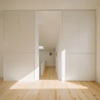 Pine floored room with built in white cupboards and a doorway to the stair