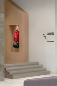 Timber clad niche displaying a red jacket above wide grey steps, with an arrow sign pointing upstairs, Housing CARNIVAL by Studio Profile