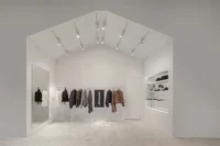 White gabled room with jackets on a rail and shelves set into the side walls, Housing CARNIVAL by Studio Profile