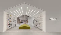 Sneaker walls inside a white gabled opening with radiating light strips and a green bench, Housing CARNIVAL by Studio Profile