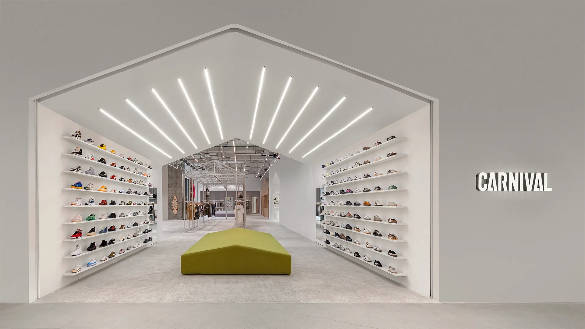 Sneaker walls inside a white gabled opening with radiating light strips and a green bench, Housing CARNIVAL by Studio Profile