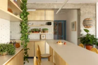 Long pale counter top extending from the kitchen toward the dining area and blue framed door