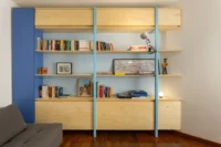 Study wall with plywood shelving on light blue uprights, a blue panel and a sofa bed