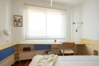 Bedroom with a built in desk running under the window and blue and pink drawer fronts