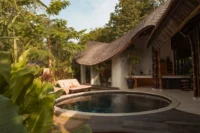 Kaymana villa with a curving thatched roof beside a round plunge pool and sun loungers