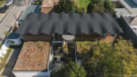 Aerial view of the corrugated dark roof, planted roof terraces and garden trees, Los Navegantes House