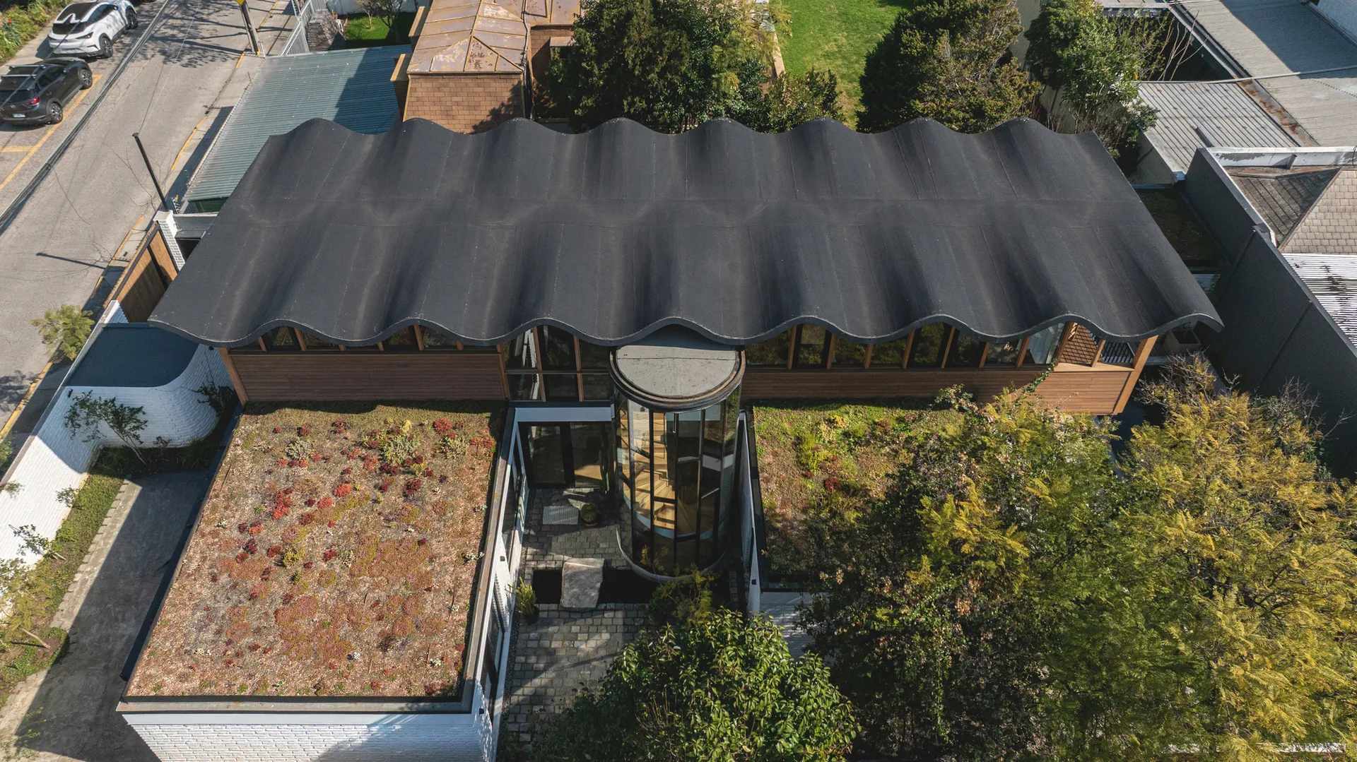 Aerial view of the corrugated dark roof, planted roof terraces and garden trees, Los Navegantes House