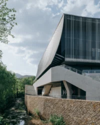 Sharp corner of the theater rising above a stone embankment over a stream, Moganshan Liaoyuan Theater by One Design