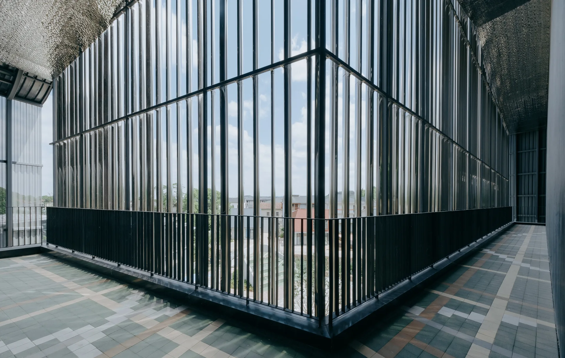 Terrace behind a screen of tall stainless steel tubes looking out over the village, Moganshan Liaoyuan Theater by One Design