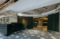 Foyer with a terrazzo floor, a dark counter and a curved curtain under a ring of lights, Moganshan Liaoyuan Theater by One Design