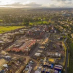 Aerial view of a large housing estate under construction surrounded by existing streets and fields