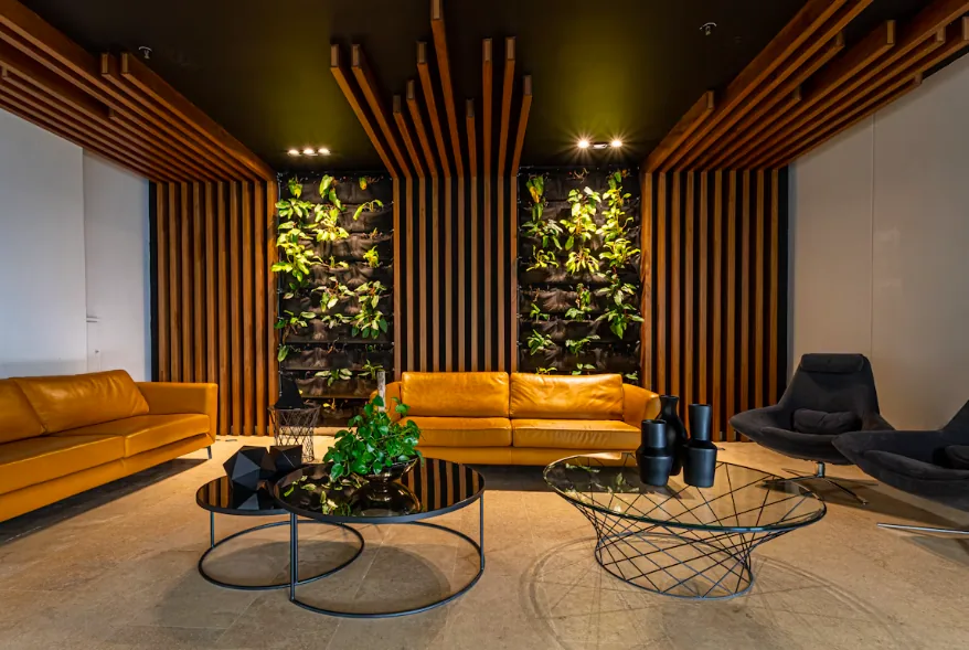 Office lounge with leather sofas facing two living wall panels between timber slats