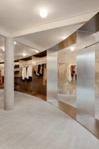 Curving clothing display with stainless steel panels and a round column inside the store