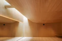 Dance studio wrapped in warm wood with a curved ceiling rising toward light