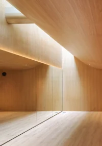 Wood lined dance studio with a long mirror and daylight falling from above