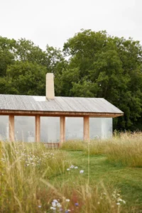 Barn with a skylight and concrete chimney on its ridge seen along a mown grass path, The Makers Barn by HUTCH design