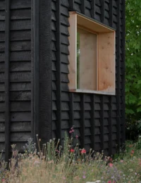 Projecting timber window box on a wall of blackened overlapping boards, The Yakisugi Cabin