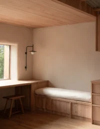Window seat with a cushion and a built in desk against clay plastered walls, The Yakisugi Cabin