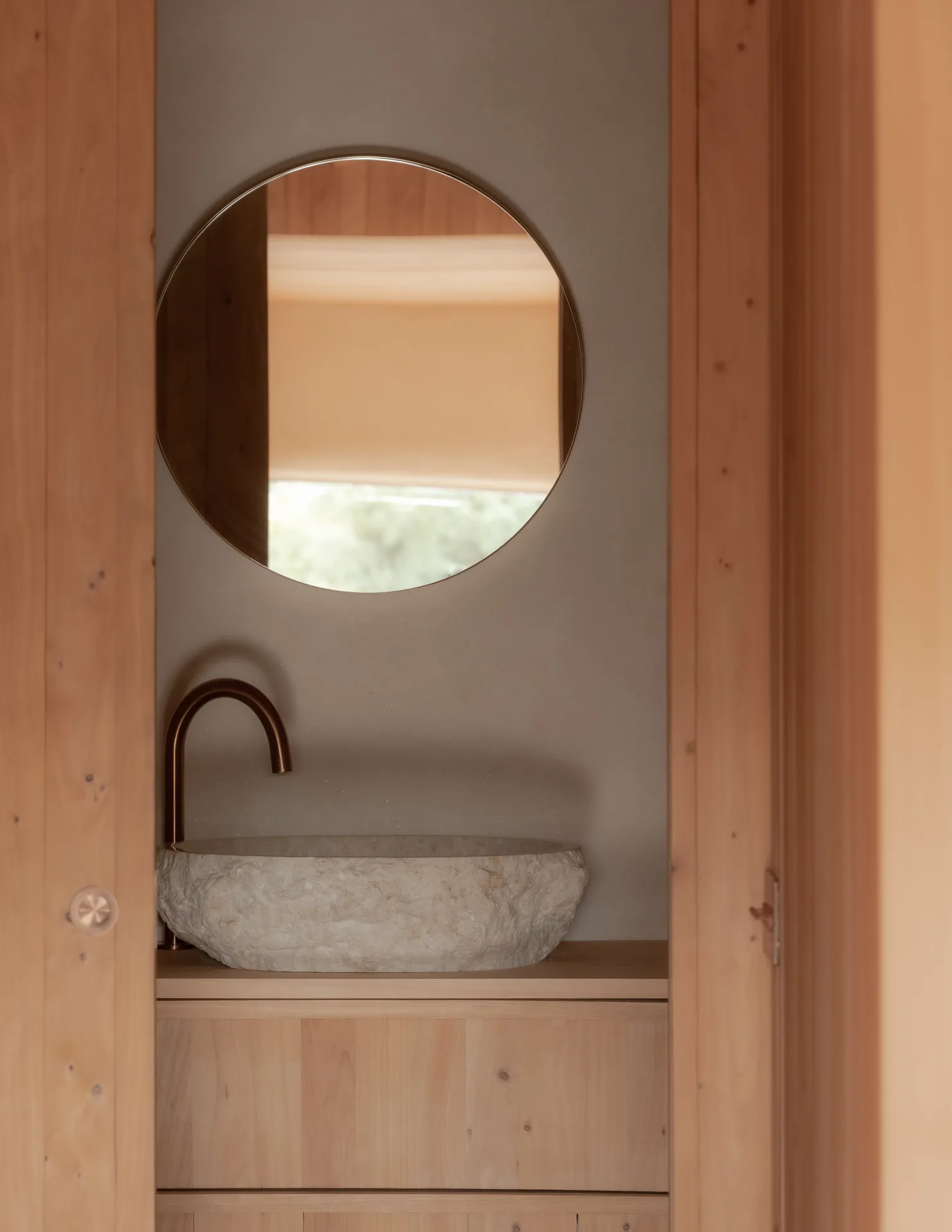 Stone basin with a copper spout below a round mirror between timber jambs, The Yakisugi Cabin