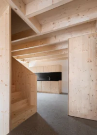 Spruce clad stair volume and open kitchen under exposed timber joists