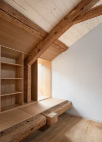 Built in shelves and a timber bench under a heavy old roof beam beside a white wall