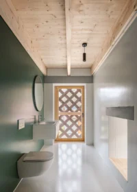 Bathroom with a green wall, round mirror and a lattice patterned door at the end