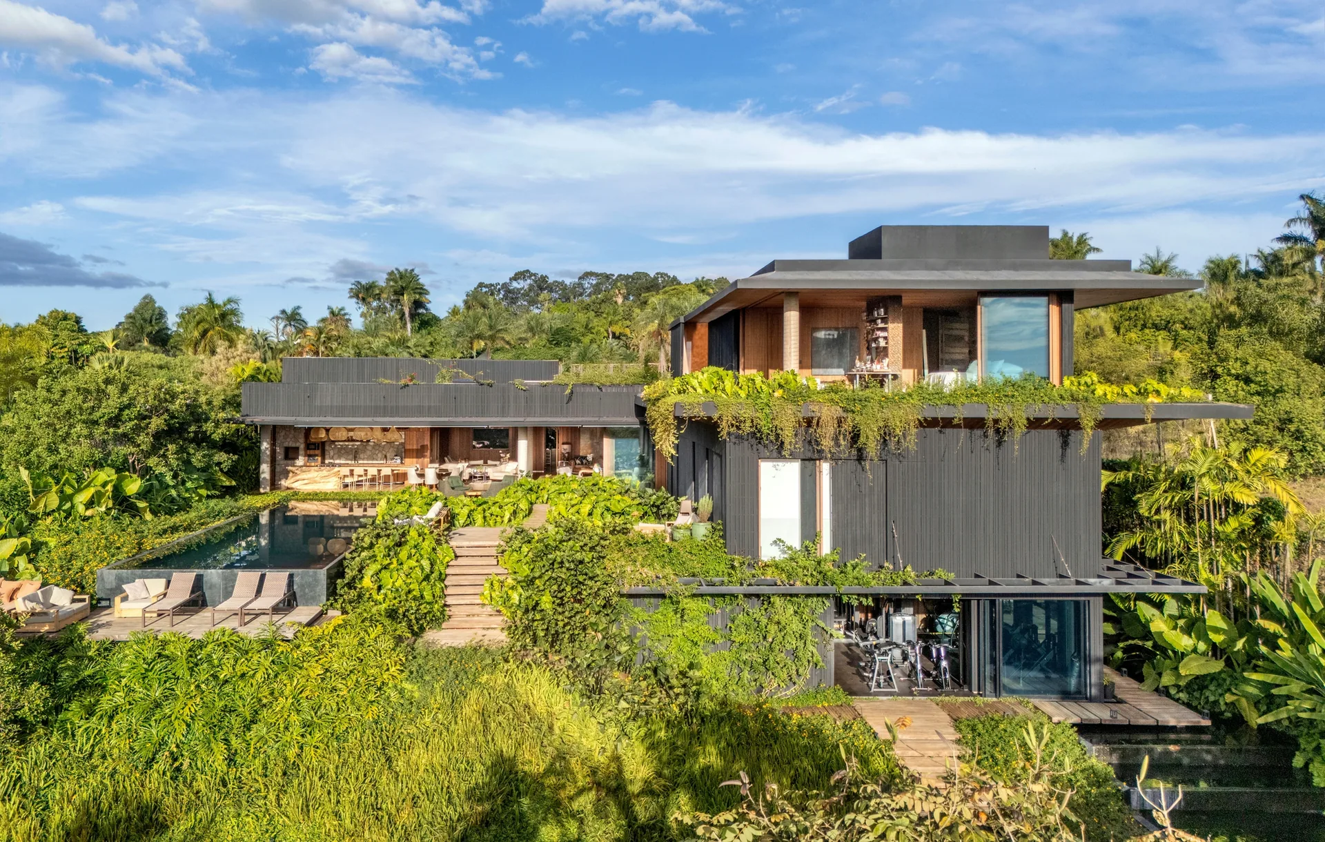 House seen from the bottom of the sloping garden with terraces, steps and trailing greenery, Vista House by Studio Gontijo Arquitetura