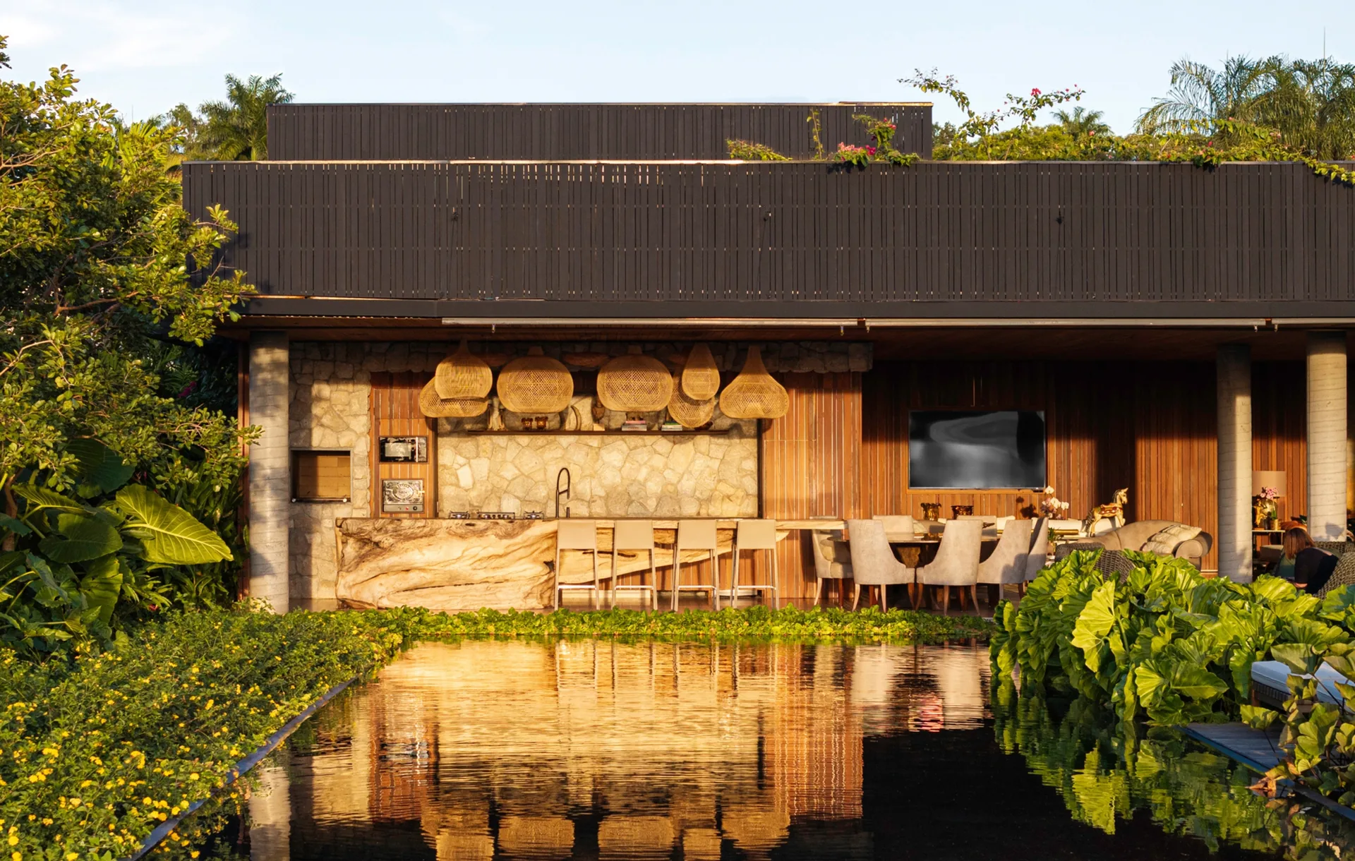 Lounge pavilion with a stone fireplace wall and timber ceiling reflected in a black pool, Vista House by Studio Gontijo Arquitetura