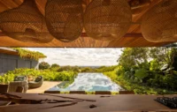 View from under woven pendant lamps across the pool toward the distant horizon, Vista House by Studio Gontijo Arquitetura
